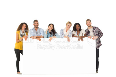 Smiling group of young friends leaning on large poster