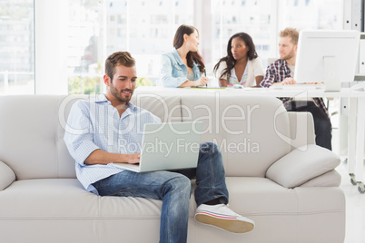 Young designer working on his laptop on the couch