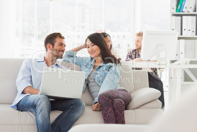 Smiling designers working together on laptop on the couch