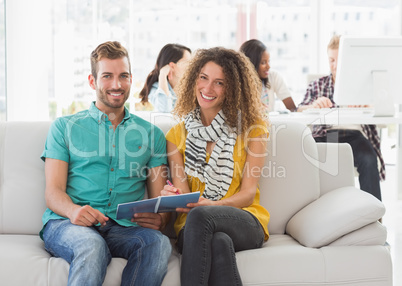 Smiling designers working together on the couch looking at camer