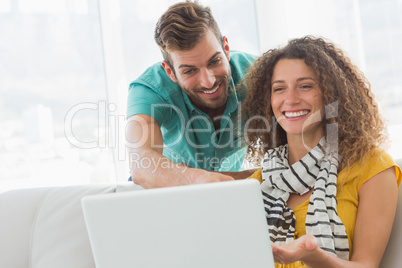 Smiling woman on the couch showing her co worker her laptop