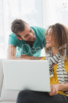 Smiling woman on the couch showing her colleague her laptop