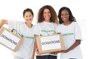 Happy team of volunteers smiling at camera holding donations box