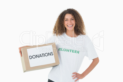 Smiling volunteer holding a box of donations with hand on hip