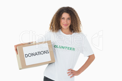 Happy volunteer holding a box of donations with hand on hip