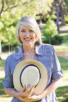 Woman holding sunhat in park
