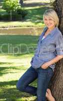 Woman leaning on tree trunk in park