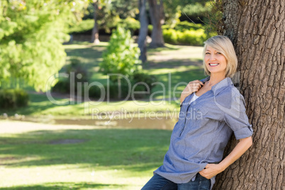 Beautiful woman leaning on tree trunk