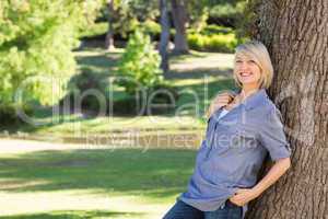 Beautiful woman leaning on tree trunk