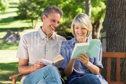 Couple reading books on bench