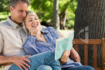 Couple reading book on park bench