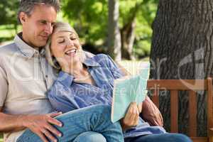 Couple reading book on park bench