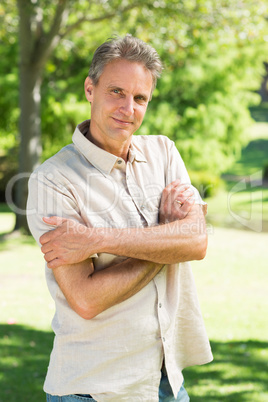 Man with arms crossed in park