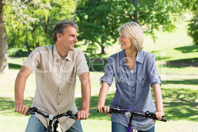 Couple riding bicycles in park