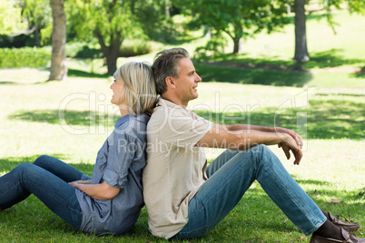 Couple sitting back to back in park