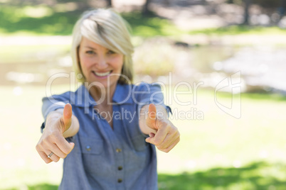 Woman gesturing thumbs up in park Woman gesturing thumbs up in park