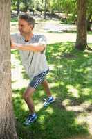 Man stretching against tree