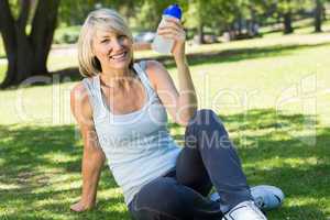 Relaxed woman holding water bottle in park