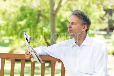 Businessman reading newspaper in park
