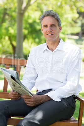 Businessman holding newspaper in park