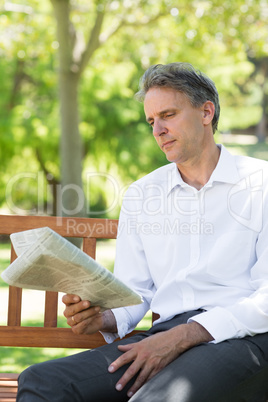 Businessman reading newspaper in park