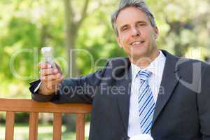 Businessman with cellphone at park