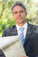 Mature businessman with newspaper in park