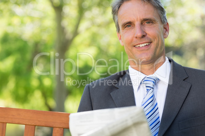 Businessman with newspaper in park