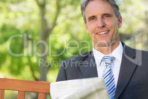 Businessman with newspaper in park