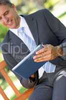 Businessman using digital tablet in park