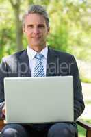 Confident businessman with laptop at park