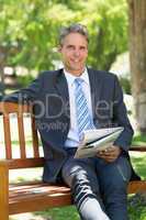 Businessman with newspaper sitting in park