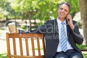 Businessman with disposable cup answering cellphone