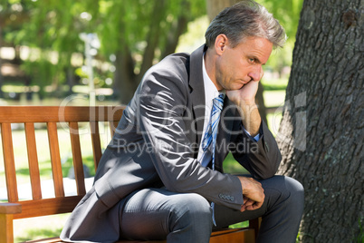 Depressed businessman sitting on park bench