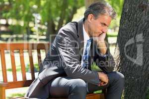 Depressed businessman sitting on park bench