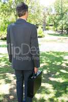 Businessman carrying briefcase in park