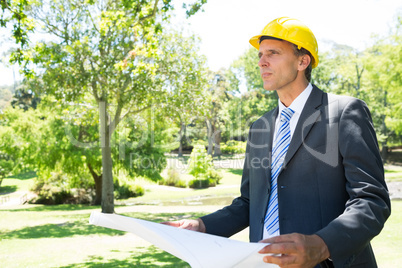 Businessman looking away while holding blueprint