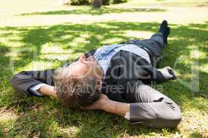 Businessman lying on grass in park