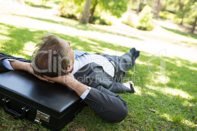 Businessman resting head on briefcase