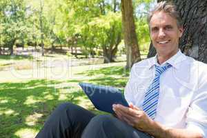 Businessman with digital tablet in park