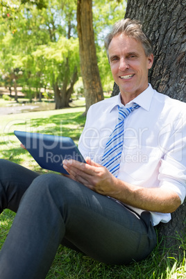 Confident businessman with digital tablet in park