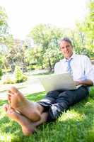 Businessman with laptop sitting in park