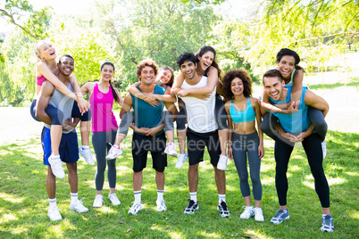 Men piggybacking female friends in the park