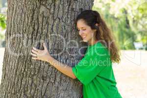 Beautiful environmentalist embracing tree trunk