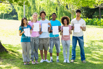 Multiethnic friends holding blank papers