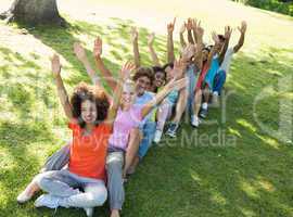 Row of excited friends raising hands in park