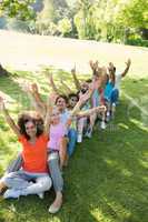 Row of friends raising hands in park