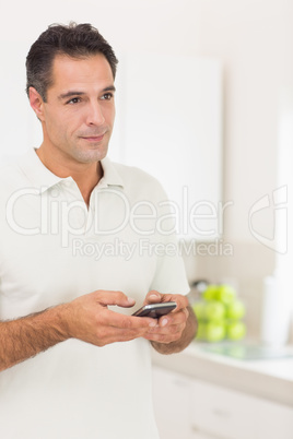 Smiling man text messaging at home