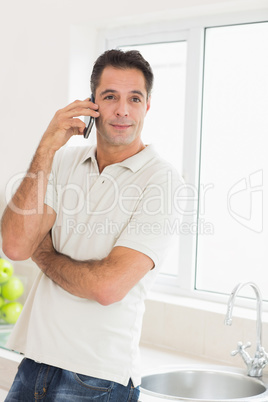 Handsome man using mobile phone in kitchen