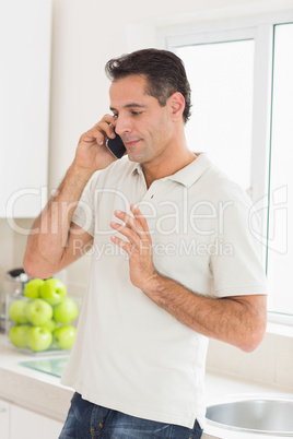 Handsome man using mobile phone in kitchen